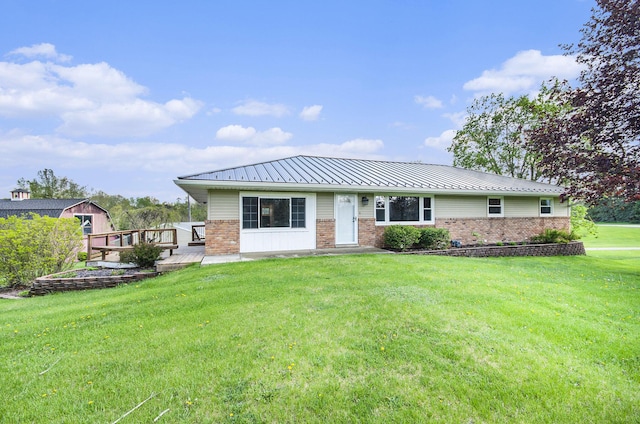 back of house with brick siding, a yard, a standing seam roof, and metal roof