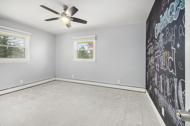 carpeted empty room with healthy amount of natural light, a ceiling fan, baseboards, and a baseboard radiator