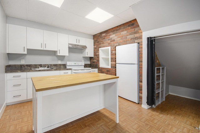 kitchen with white appliances, wooden counters, under cabinet range hood, a drop ceiling, and white cabinets