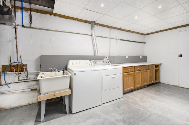 clothes washing area featuring cabinet space, washer and dryer, and concrete block wall
