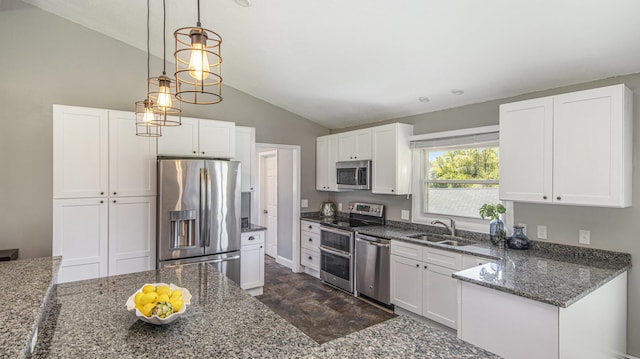 kitchen featuring appliances with stainless steel finishes, a sink, lofted ceiling, white cabinets, and dark stone counters
