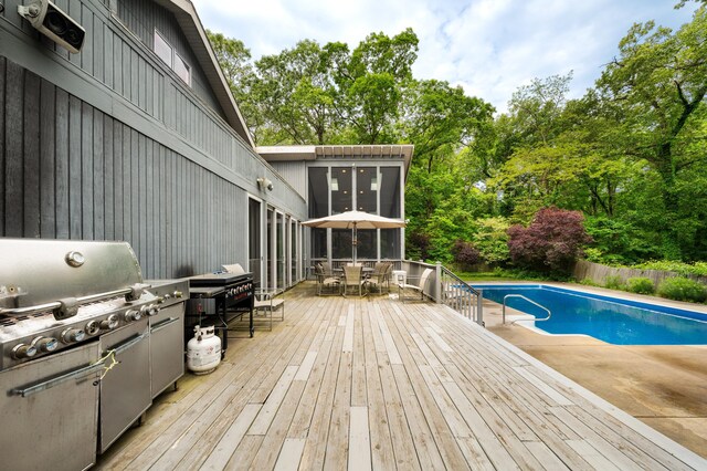 50102 Alpine Blvd, New Buffalo, MI 49117 - view of pool featuring outdoor dining space, a wooden deck, view of wooded area, a sunroom, and grilling area