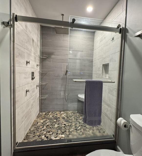 full bathroom featuring toilet and a stall shower