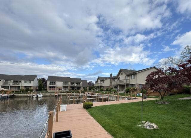 dock featuring a residential view, a lawn, and a water view