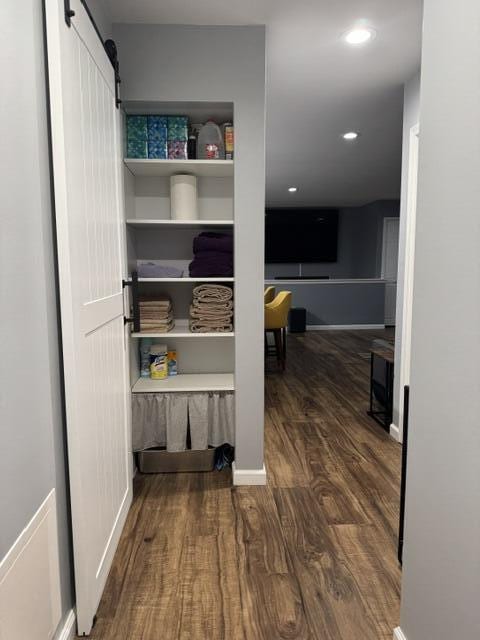 hall with wood finished floors, a barn door, and baseboards