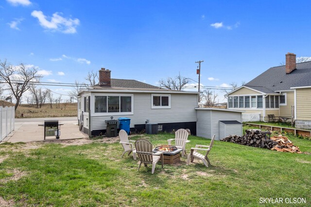 1520 Beach St, Muskegon, MI 49441 - back of house featuring a fire pit, central air condition unit, an outbuilding, a chimney, and a shed