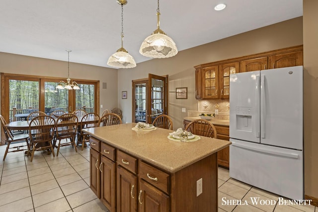 903 10 Mile Rd NW, Sparta, MI 49345 - kitchen with white fridge with ice dispenser, light tile patterned floors, a center island, brown cabinetry, and decorative light fixtures