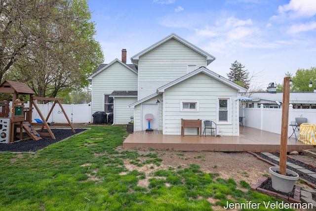 back of property featuring a wooden deck and a playground