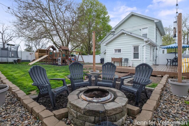 view of patio / terrace with a fire pit, a trampoline, a playground, and a deck