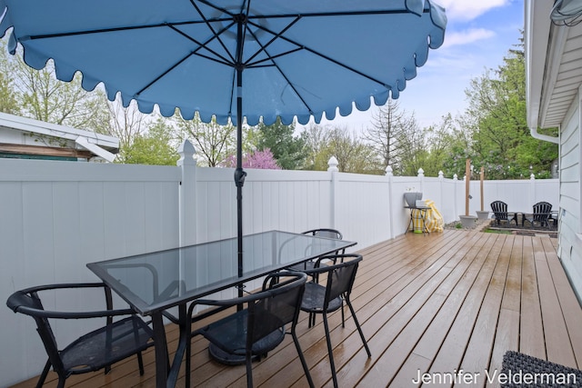 wooden deck with outdoor dining area and fence