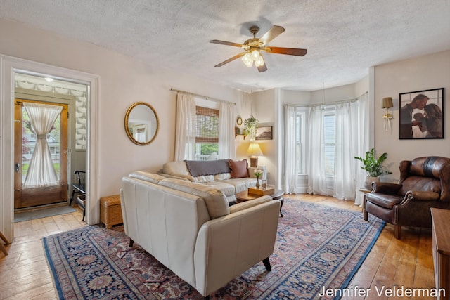 living area featuring a textured ceiling, ceiling fan, and light wood-type flooring