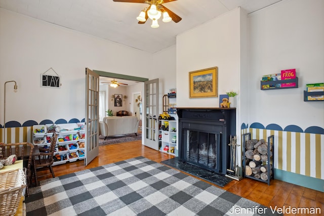 living room with a ceiling fan, a fireplace with flush hearth, french doors, and wood finished floors