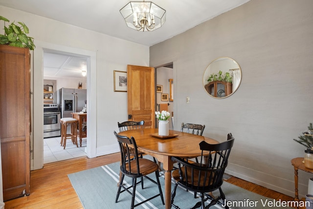 dining space featuring light wood finished floors, a chandelier, and baseboards