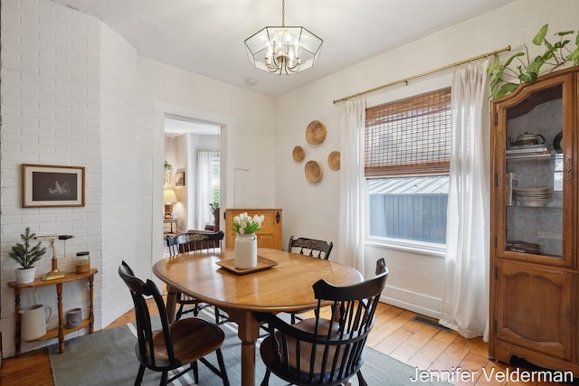 dining room featuring healthy amount of natural light, light wood-style flooring, a chandelier, and baseboards