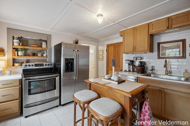 kitchen featuring stainless steel appliances, a sink, light tile patterned floors, light countertops, and backsplash
