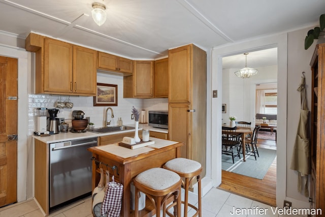 kitchen featuring a sink, appliances with stainless steel finishes, light tile patterned floors, light countertops, and backsplash