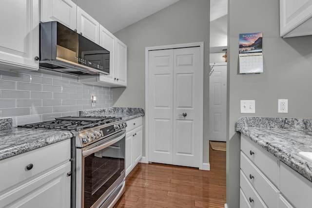 kitchen featuring stainless steel gas range oven, black microwave, tasteful backsplash, white cabinets, and wood finished floors