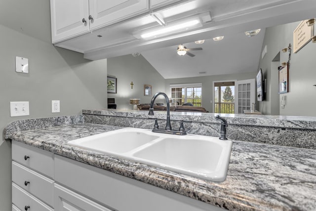 kitchen with a sink, lofted ceiling, a ceiling fan, white cabinets, and open floor plan