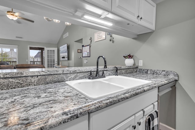 kitchen with a sink, white cabinets, a ceiling fan, vaulted ceiling, and stainless steel dishwasher