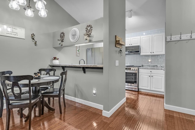 dining space with wood-type flooring, baseboards, and a chandelier