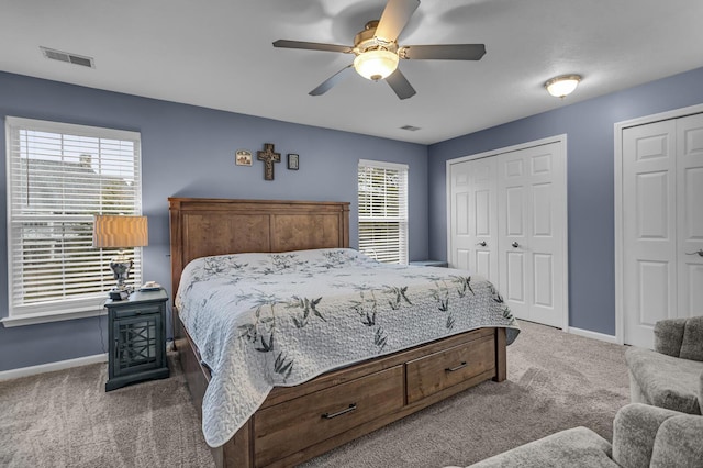 carpeted bedroom featuring baseboards, two closets, and ceiling fan