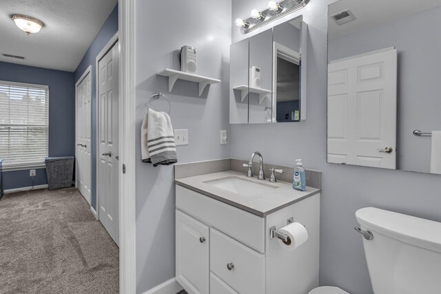 half bath with toilet, vanity, and baseboards