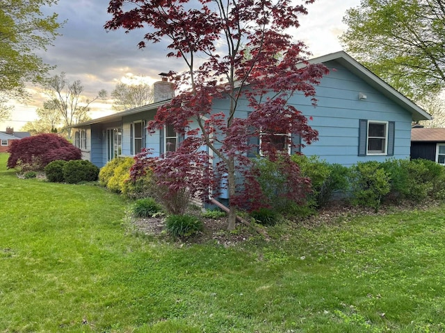 view of side of home featuring a chimney and a lawn