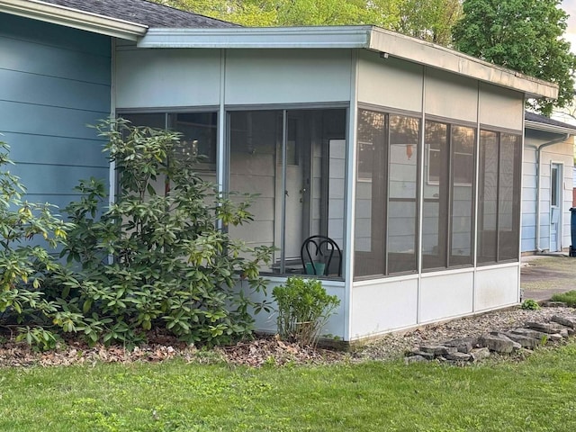 view of side of home featuring a sunroom and a shingled roof