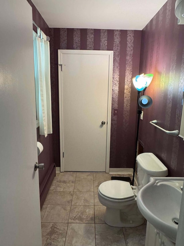 bathroom with wallpapered walls, a sink, toilet, and tile patterned floors