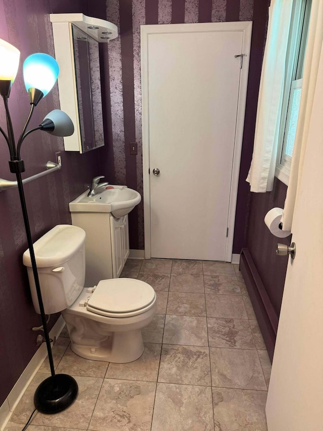 half bathroom with toilet, vanity, and baseboards