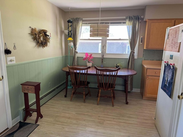 dining space featuring a wainscoted wall and light wood finished floors