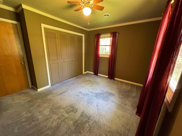 unfurnished bedroom with carpet flooring, a closet, crown molding, baseboards, and ceiling fan