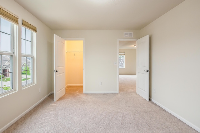2767 St Regis Way, Ann Arbor, MI 48105 - unfurnished bedroom with light colored carpet, baseboards, and a walk in closet