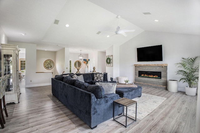 living room with lofted ceiling, light wood-style flooring, a glass covered fireplace, a ceiling fan, and recessed lighting