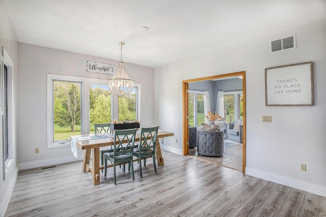 dining room featuring light wood finished floors, a chandelier, and baseboards
