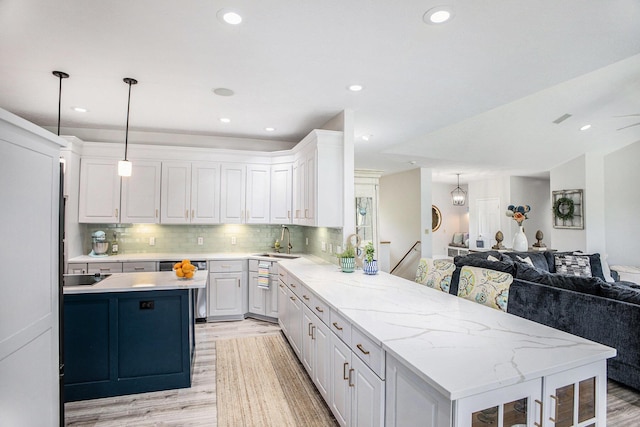 kitchen with a sink, a peninsula, light wood-style flooring, open floor plan, and white cabinetry