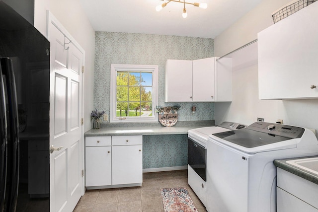 clothes washing area featuring cabinet space, washing machine and dryer, wallpapered walls, and light tile patterned floors