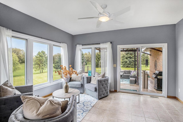 living area with baseboards, ceiling fan, and light tile patterned flooring