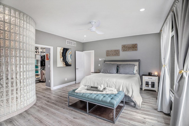 bedroom featuring wood finished floors, baseboards, a spacious closet, ceiling fan, and a closet