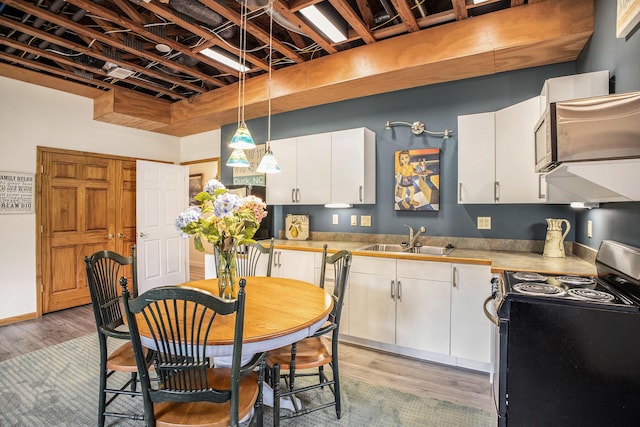 kitchen featuring electric range oven, a sink, light wood-style flooring, white cabinetry, and light countertops