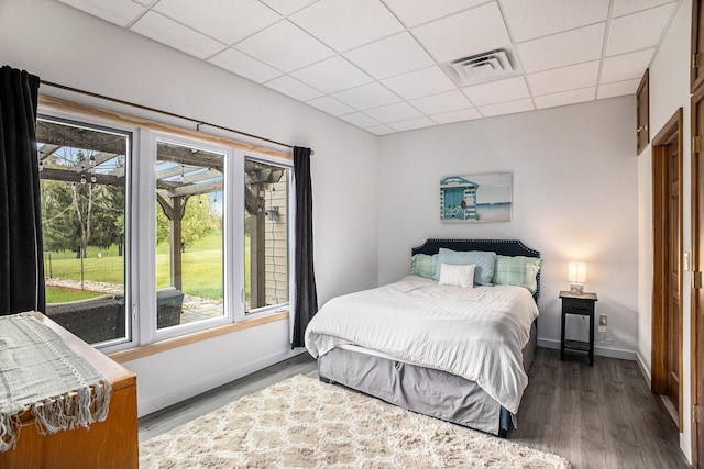 bedroom featuring multiple windows, a paneled ceiling, wood finished floors, and baseboards
