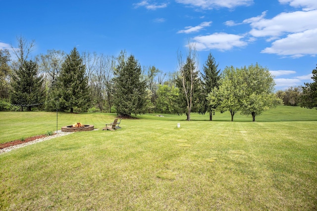 view of grassy yard with an outdoor fire pit