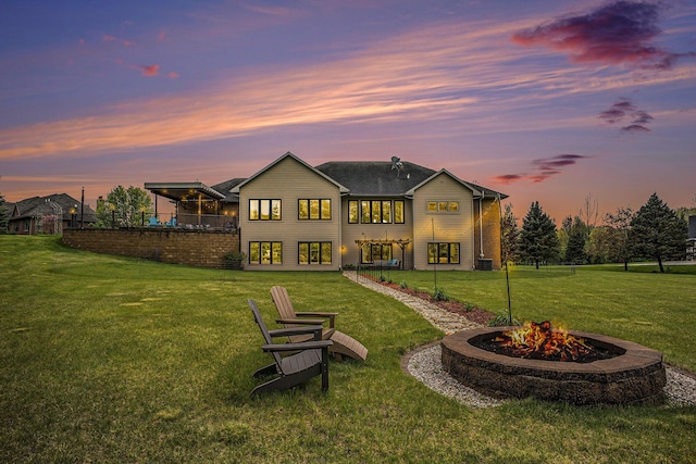 rear view of house with a fire pit, a lawn, and a balcony