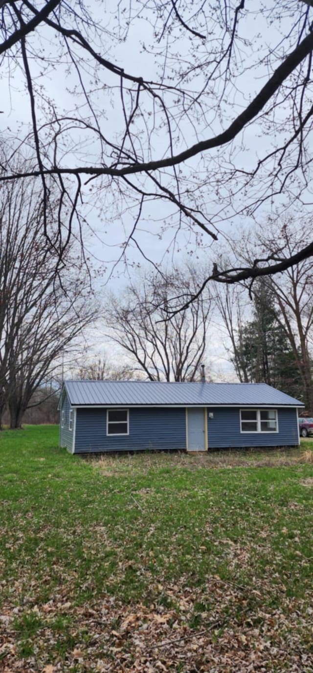 view of side of home featuring metal roof and a yard