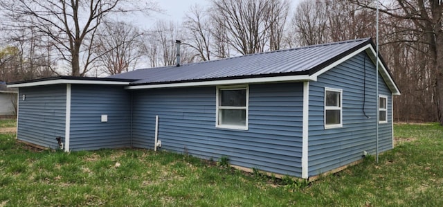 view of side of home featuring metal roof and a lawn