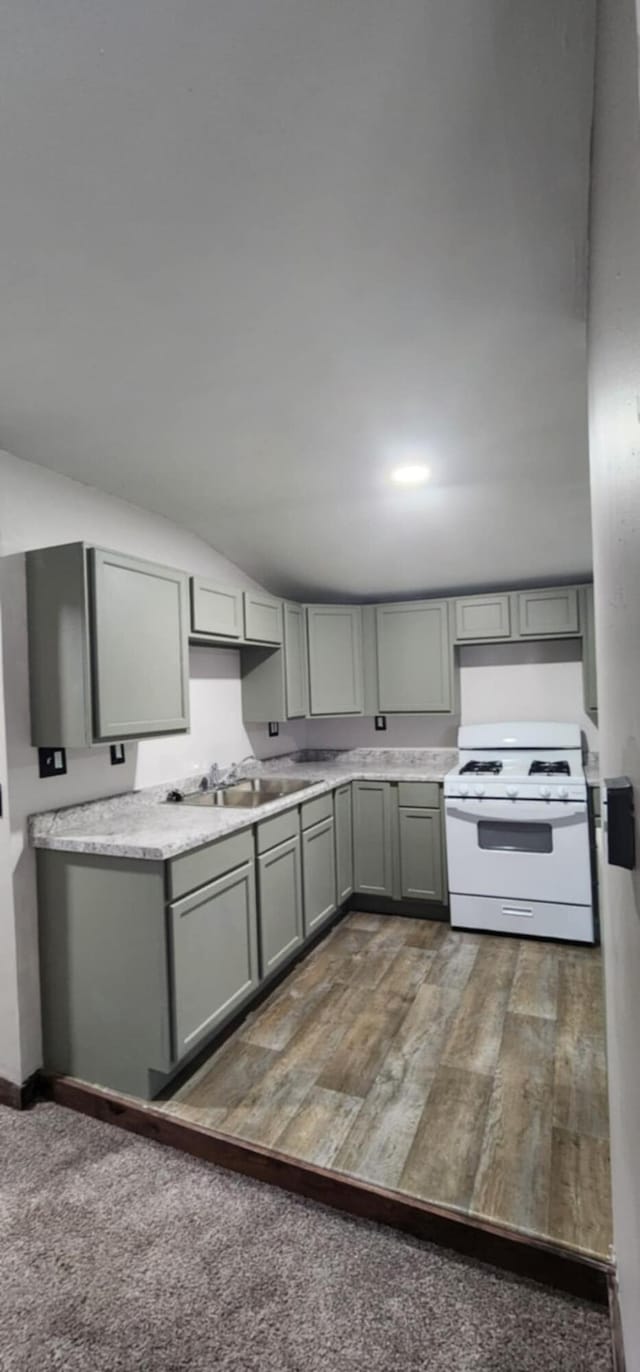 kitchen with gas range gas stove, gray cabinets, a sink, and light countertops