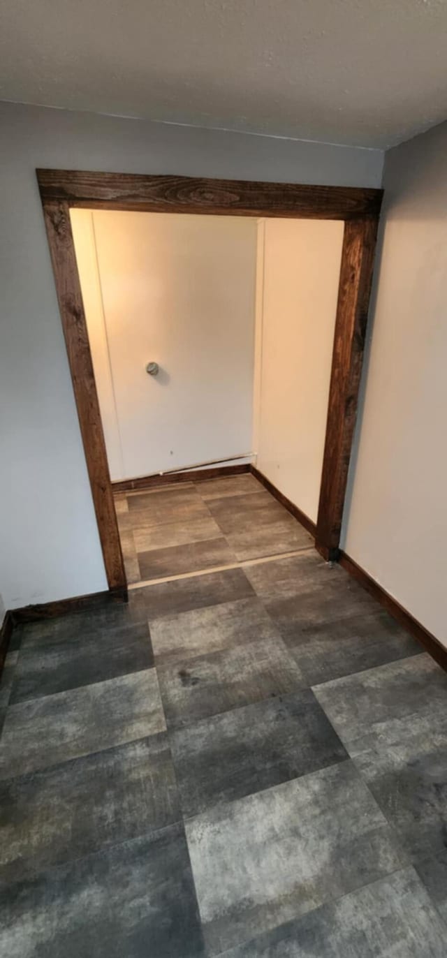 hall with baseboards and dark floors