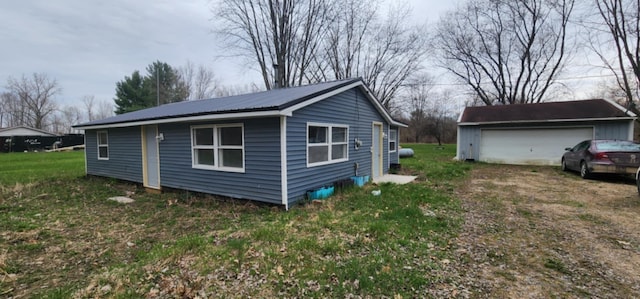 view of property exterior featuring a detached garage, an outdoor structure, and metal roof