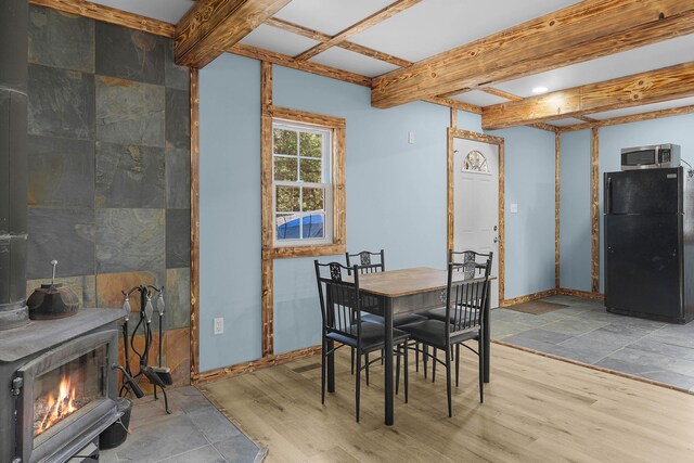 23748 Cutler Rd, Newaygo, MI 49337 - dining room with wood finished floors, beamed ceiling, baseboards, and a wood stove
