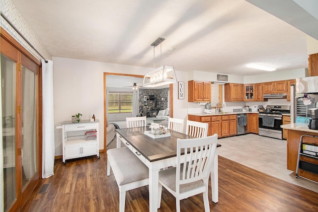 23127 Kendaville Rd, Pierson, MI 49339 - dining room featuring a stone fireplace, wood finished floors, and a ceiling fan